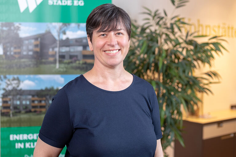 Angelique Paul-Teipel. Sie ist Prokuristin und Leiterin der Finanzen und des Services der Wohnstätte Stade eG. Frau Paul-Teipel ist mittleren Alters, hat einen dunkelbraunen Kurzhaarschnitt und trägt ein dunkelblaues T-Shirt.