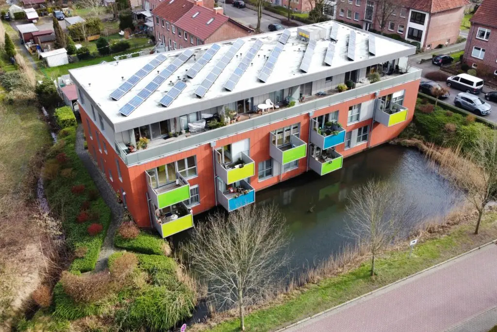dem farbenfrohen Wohnblock in der Dankersstraße 68c. Direkt auffallend ist der bunte Anstrich des Hauses in Rot und den Balkonen in Grün, gelb und blau. außerdem hat es auf seinem flachen dach eine photovolteikanlage. das letzte Stockwerk ist eine Loggia, mit großer Dachterrasse. Das Wohngebäude steht direkt an einem kleinen See.