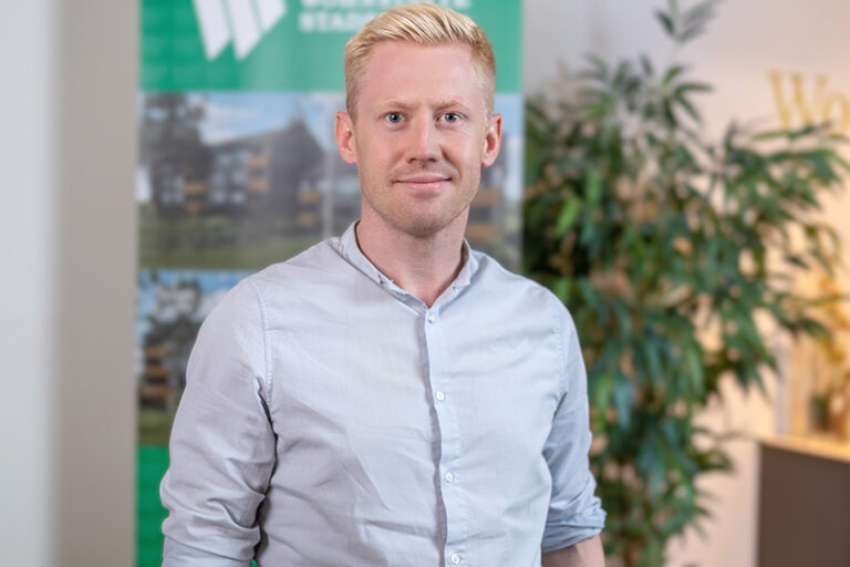 Florian Wehmann. Er ist Mitarbeiter in den Bereichen Buchhaltung und Finanzen der Wohnstätte Stade eG. Herr Wehmann ist mittleren Alters, hat einen blonden zurückgegelten Kurzhaarschnitt und trägt ein hellblaues Hemd.