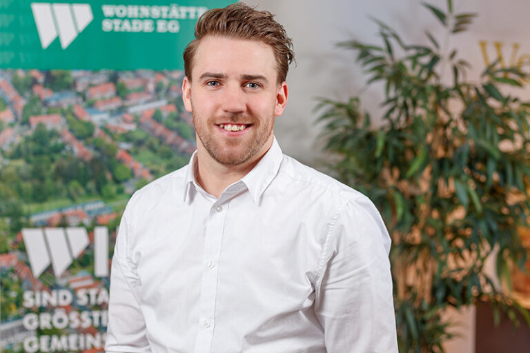 Nico von der Reith. Er ist Mitarbeiter in der Kundenbetreuung der Wohnstätte Stade eG. Herr von der Reith ist früheren Alters, hat kurze, zurückgegelte, hellbraune Haare und trägt ein weißes Hemd.