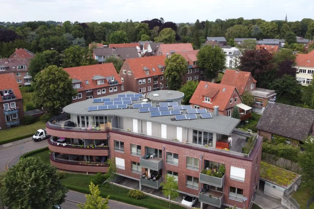 einem modernen Wohnblock in der Teichstraße 49. Direkt auffallend ist die abgerundete Gebäudeecke mit Balkonen und auf dem Dach zu sehende Photovolteikanlage. Das dritte und letzte Stockwerk ist aufgesetzt und mit einer großen Dachterrasse verseht. Des weiteren ist zu erkennen, dass alle Fenster bodentief sind und eine Tiefgarageneinfahrt rechts unter das Gebäude führt.