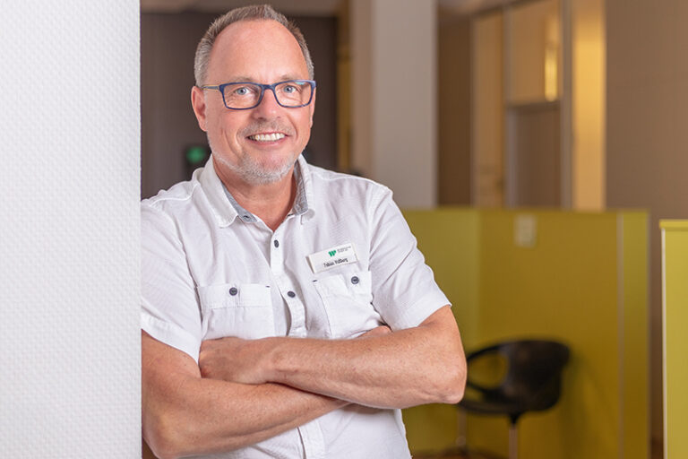 Tobias Voßberg. Er ist Teamleiter im Facility Management der Wohnstätte Stade eG. Herr Voßberg ist mittleren Alters, hat einen Kurzhaarschnitt und trägt eine Brille, sowie ein weißes kurzarmiges Hemd.